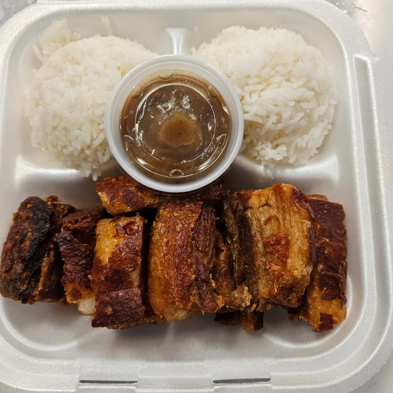 Filipino lechon kawali, crispy pork belly, with two scoops of rice and a side of sauce.